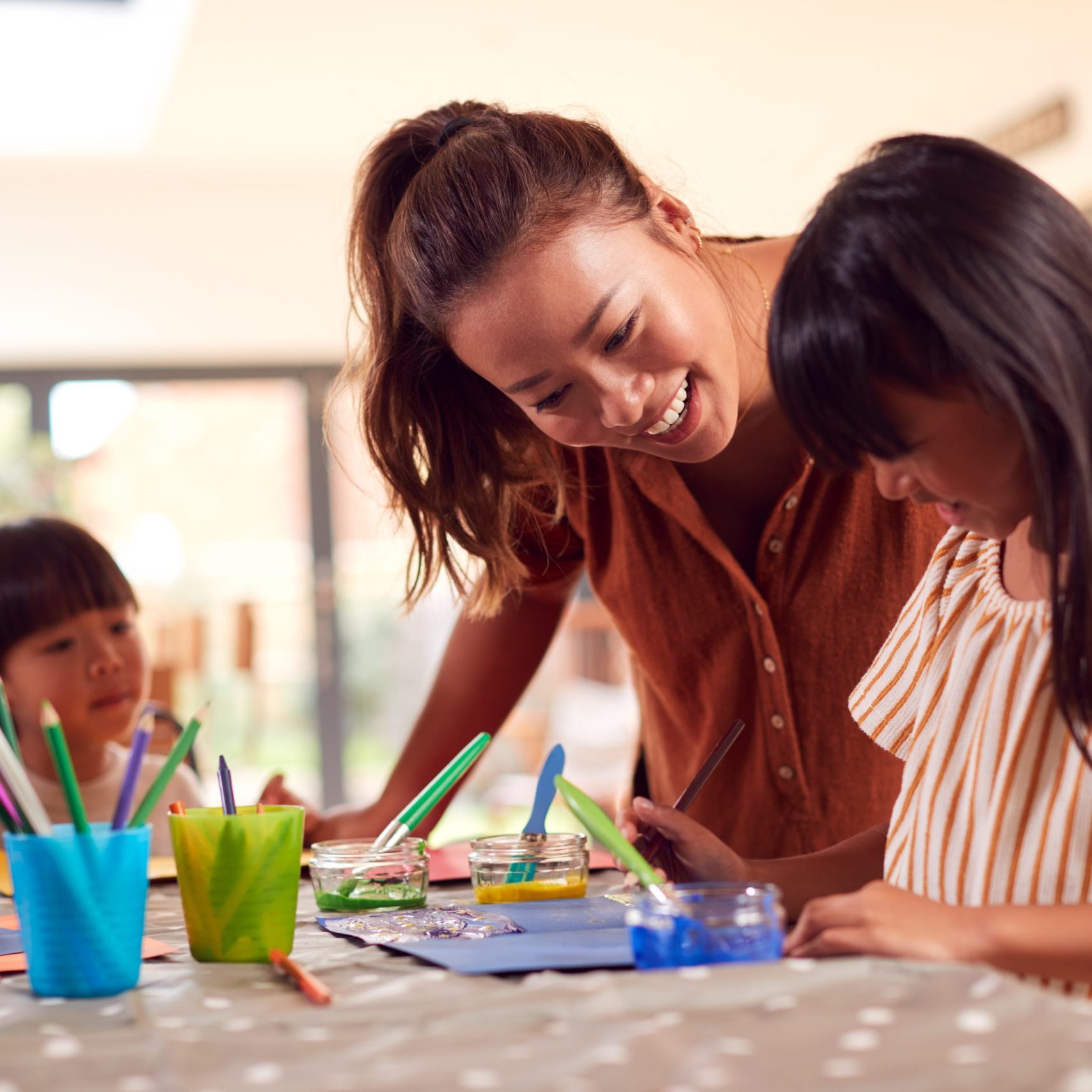 Asian Mother With Children Having Fun With Children Doing Craft On Table At Home
